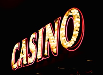 Brightly illuminated letters spell out 'CASINO' with glowing yellow bulbs and red outlines against a dark background.