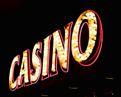 Brightly illuminated letters spell out 'CASINO' with glowing yellow bulbs and red outlines against a dark background.
